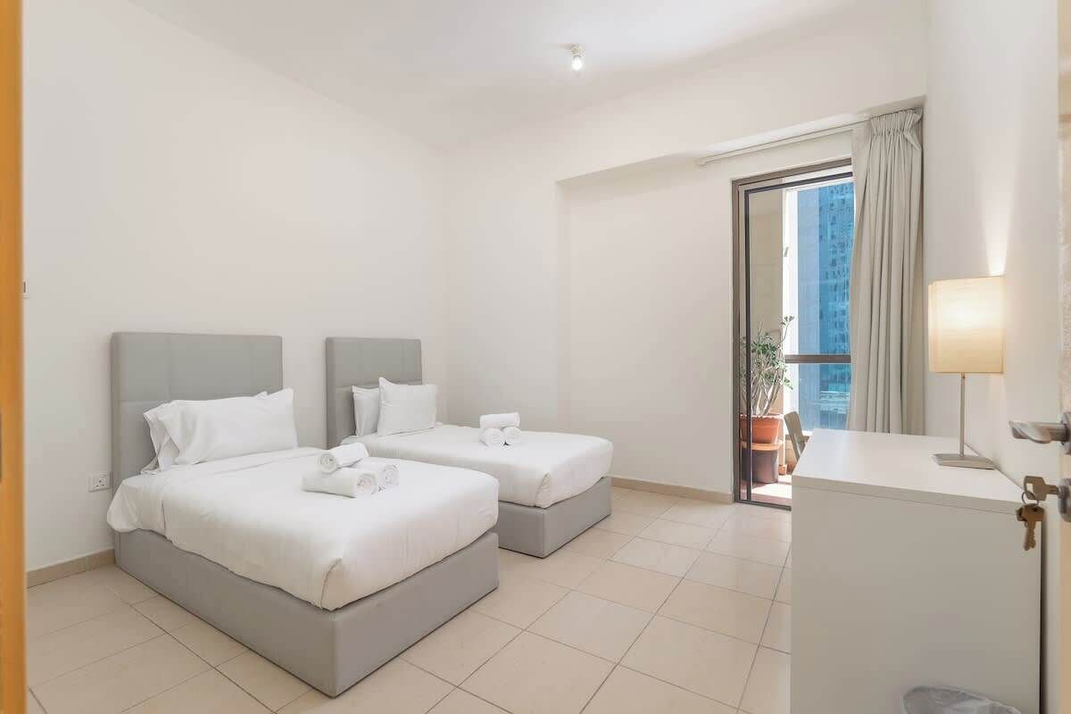 Quarto de hotel com duas camas, uma escrivaninha e vista para a cidade.