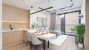 A modern kitchen with a dining area, wooden cabinets, and a large window.