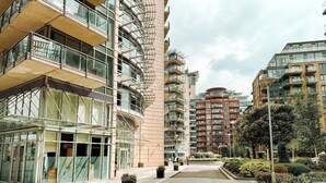 A modern apartment complex with multiple high-rise buildings, balconies, and a central courtyard with potted plants. - Londonaprt/sleeps6/gym/waterfront/wifi (London)