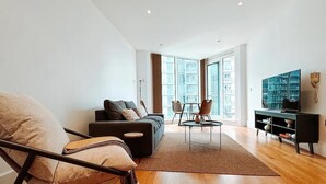 A modern living room with a sofa, armchair, coffee table, and TV stand. - Londonaprt/sleeps6/gym/waterfront/wifi (London)