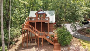 Eine Holzhütte mit Balkon und Treppe, umgeben von Bäumen.