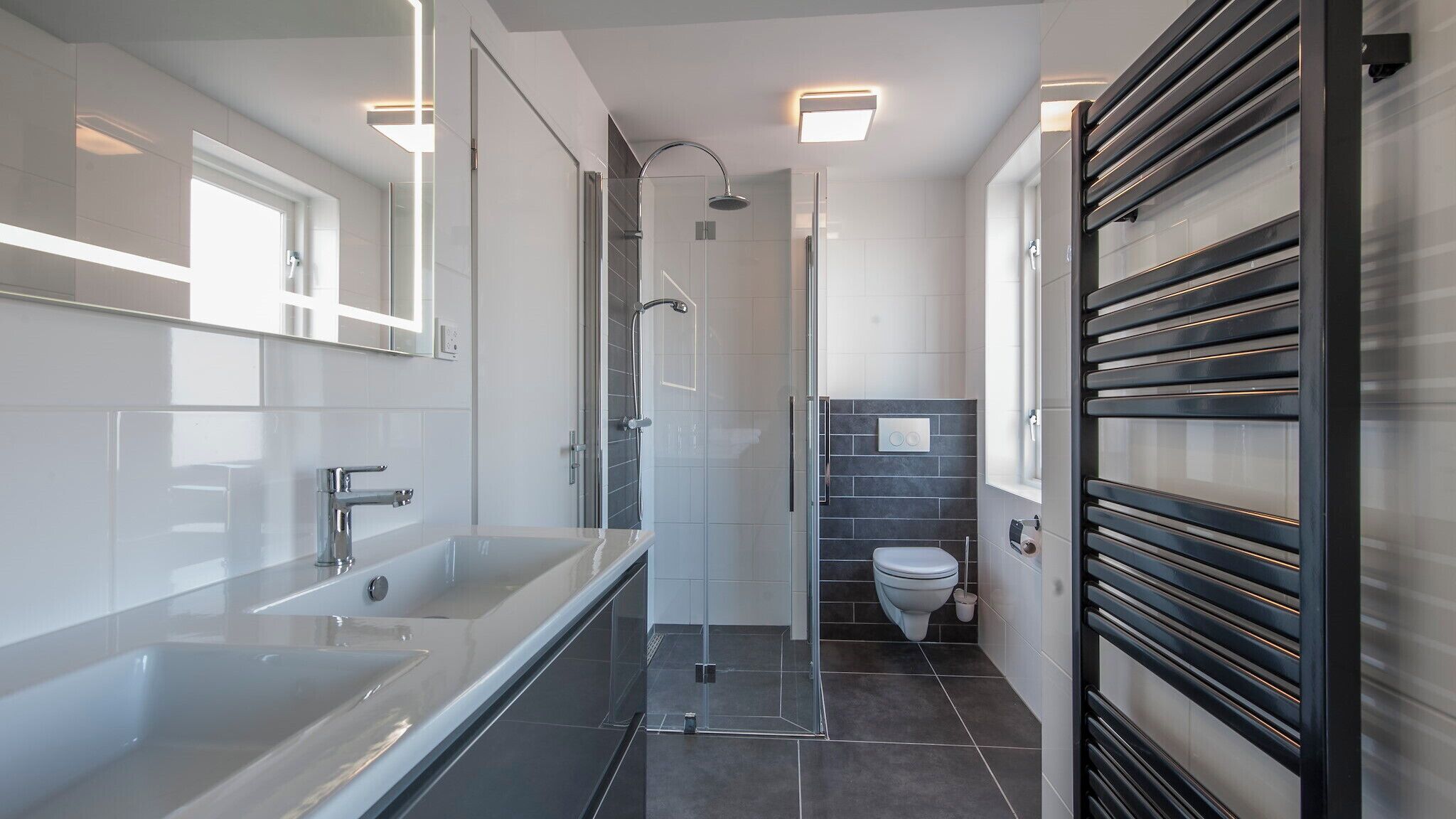 Un baño moderno con ducha envuelta en vidrio, una bañera amplia y un inodoro.