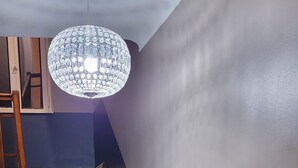 Una escalera de madera con peldaños y barandilla de madera, que conduce a un rellano con pared azul oscuro y una lámpara.