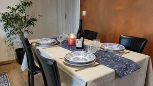 Una mesa de comedor dispuesta con platos azules y blancos, una botella de vino y una vela.