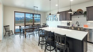 A modern kitchen with a large island, dark cabinets, and pendant lighting. - New Custom Home on 35 Acres - Amazing Mtn Views -15 Min to DGO - AC/Hot Tub (Durango)