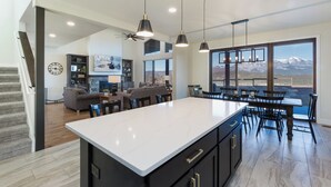 A spacious kitchen with a large island, modern pendant lighting, and a view of mountains through large windows. - New Custom Home on 35 Acres - Amazing Mtn Views -15 Min to DGO - AC/Hot Tub (Durango)