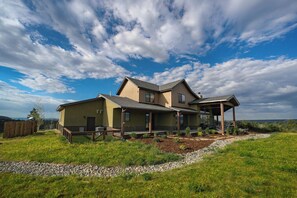 A two-story house with a covered porch and a view of the surrounding landscape.