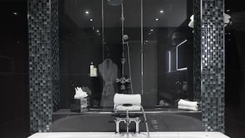 Un baño moderno con una bañera grande, cabina de ducha con paredes de cristal y un espejo que refleja la habitación.