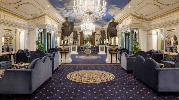 Eine luxuriöse Lobby mit einem prächtigen Kronleuchter, Marmorsäulen und klassischen Statuen.