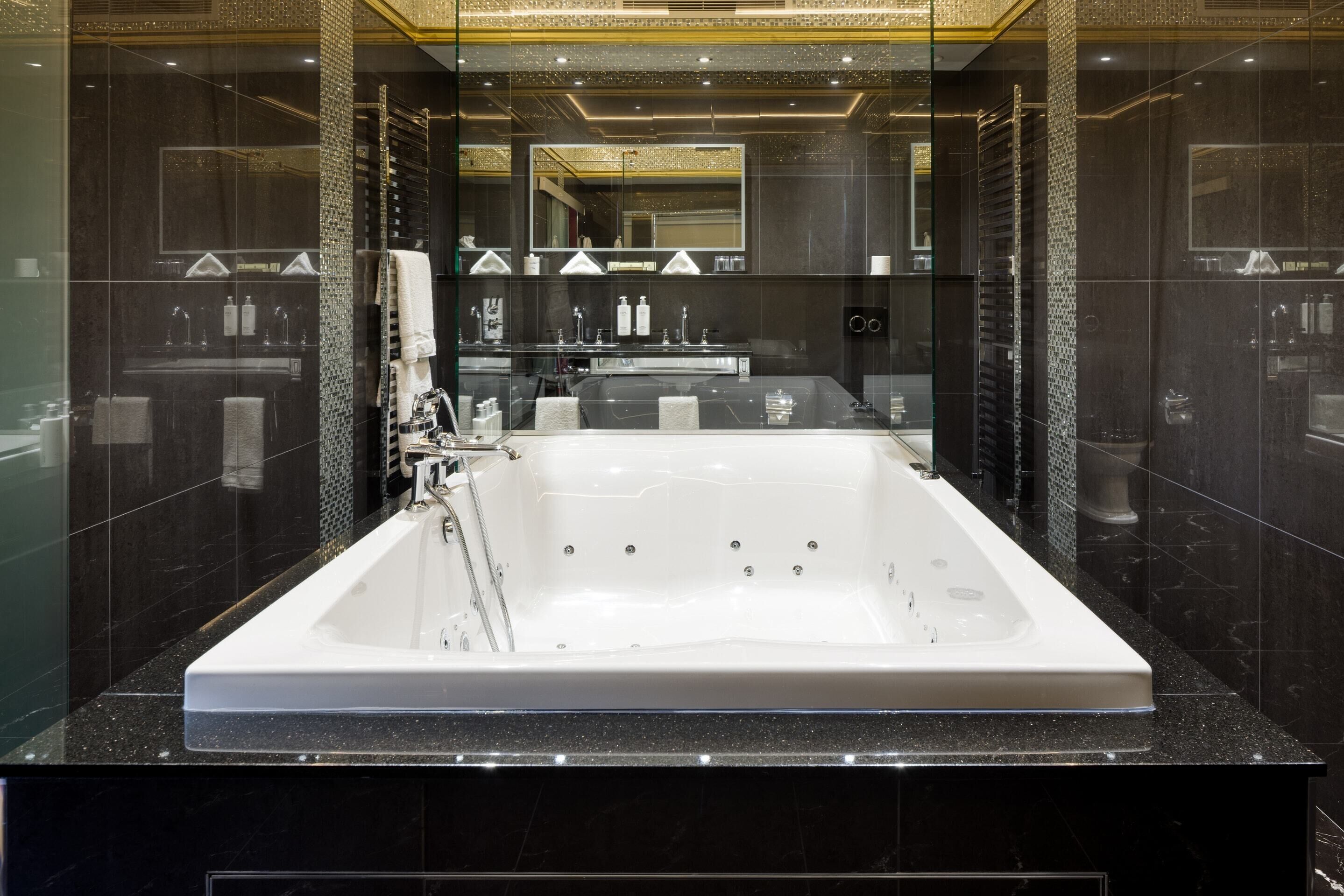 A modern bathroom with a large bathtub, a glass-enclosed shower, and a vanity with a mirror.
