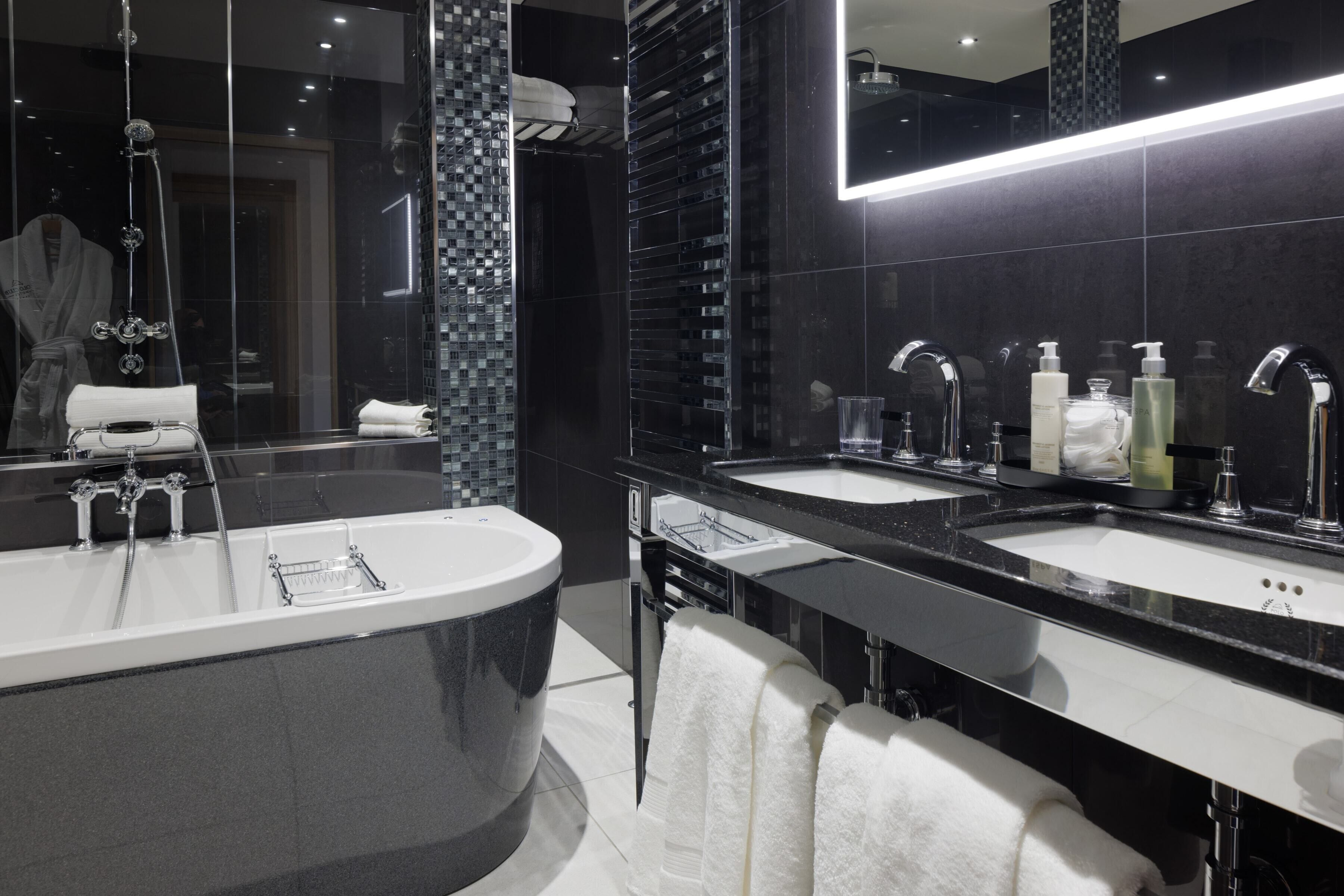 Un baño moderno con un espejo grande, dos lavabos y una bañera.