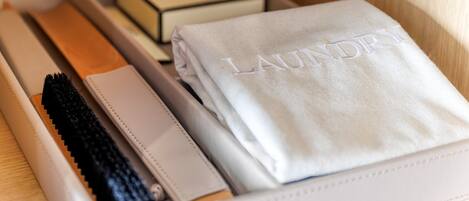 Una caja de almacenaje ordenada con una toalla doblada que dice "LAUNDRY" y un cepillo para el pelo negro.