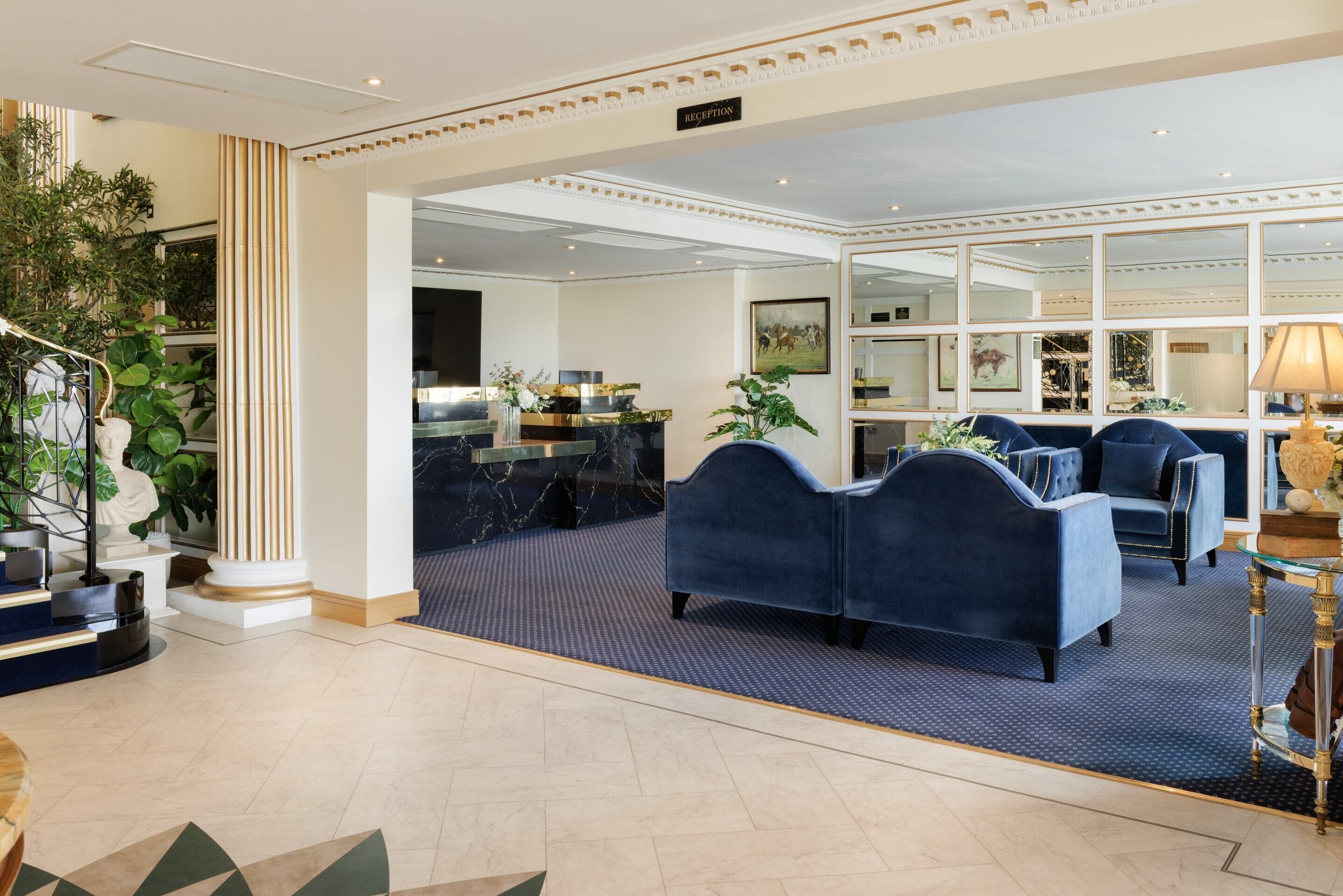 A reception area with a reception desk, blue upholstered sofas, and a mirror wall.