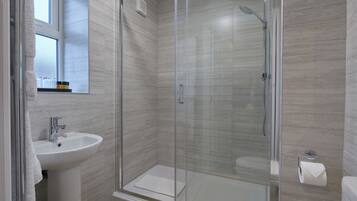 A modern bathroom with a glass-enclosed shower, a white sink, and a toilet.