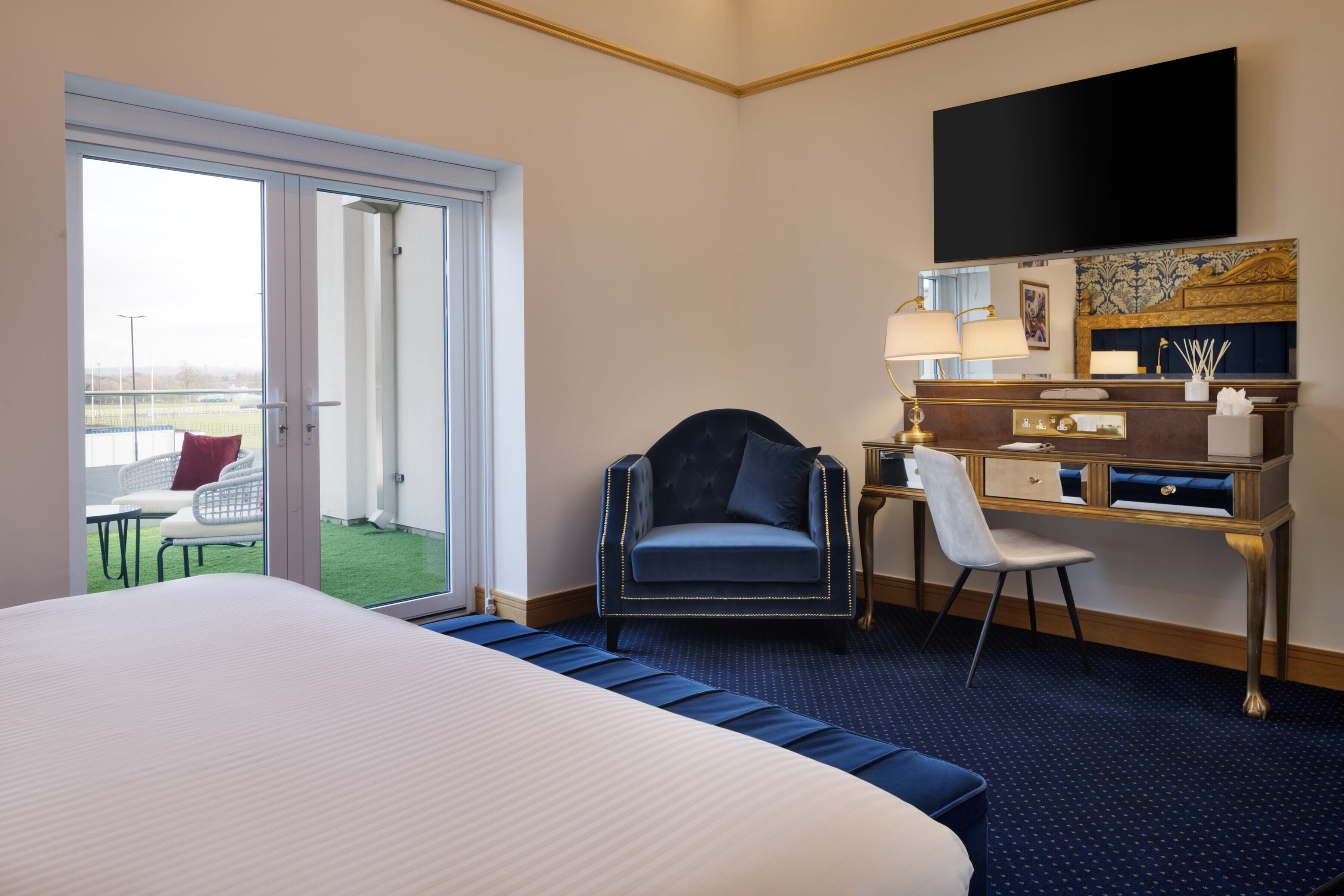 Camera d'albergo con un letto grande, una scrivania con sedia, una televisione a muro e vista sull'esterno tramite una porta scorrevole.