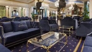 Eine luxuriöse Hotelhalle mit bequemen Sitzgelegenheiten, aufwendigen Kronleuchtern und klassischen Statuen.