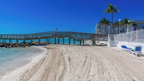 Ein Strand mit einer Holzsteg, blauem Himmel und einem Gebäude mit einem Balkon.