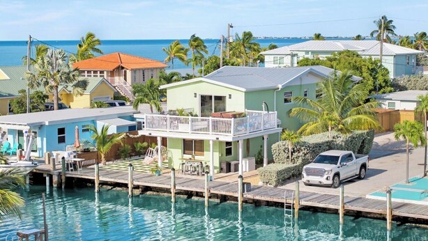 Zona residencial costera con casas, un muelle y una vista despejada del océano.