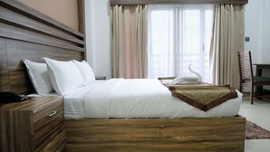 Una cama bien hecha con sábanas blancas, un cabecero de madera y una almohada con forma de cisne.