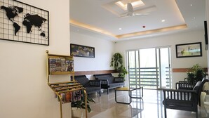 Un moderno hall de hotel con un mapa mundial, un atril con revistas, sofás, una mesa de centro y un ventanal con vistas.