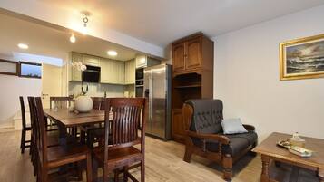 A dining area with wooden chairs and a table, a sofa, and a small table with decorative items.