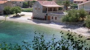 A coastal building with a stone facade, a red roof, and a small porch. - House of Green Experience (Omis)