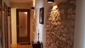 A hallway with wooden flooring, a stone wall, and a door. - Charming Rooms & Apartments Stelio (Marcana)