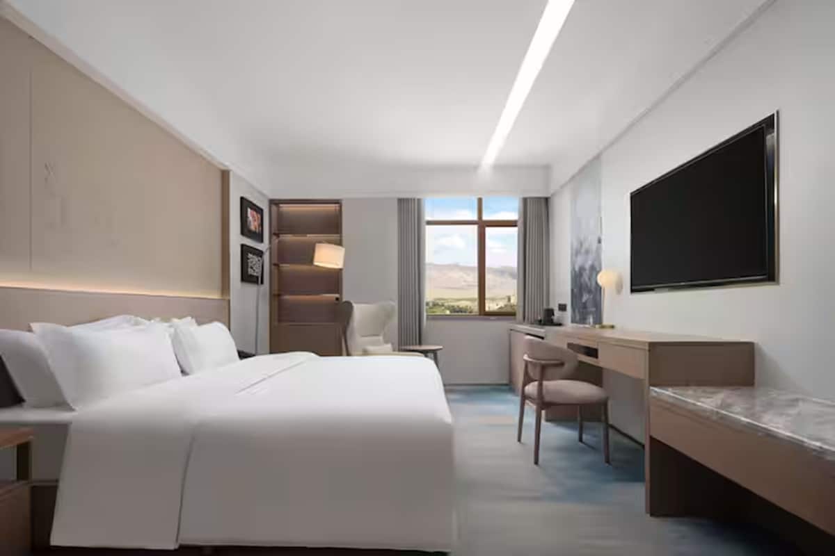 Una habitación de hotel moderna con una cama grande, un escritorio y un televisor.