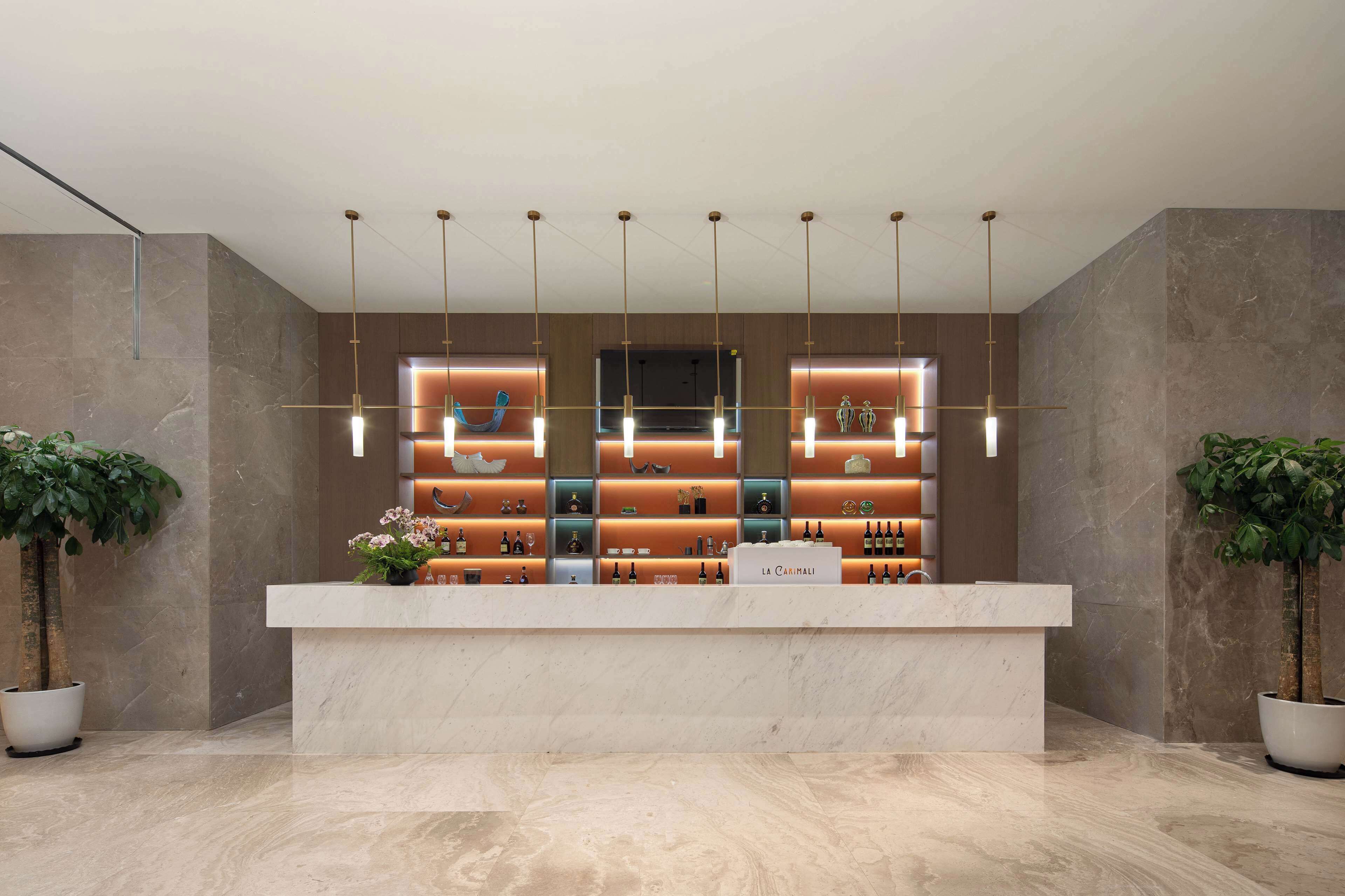 A reception area with a marble counter, hanging pendant lights, and potted plants.