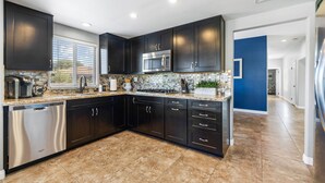 A modern kitchen with dark cabinetry, stainless steel appliances, and a tiled backsplash.
