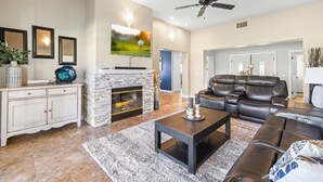 A living room with a fireplace, leather sofa, and a flat-screen TV mounted on the wall.