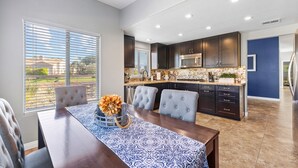 A modern kitchen with dark cabinets, a stainless steel microwave, and a large island with a sink.