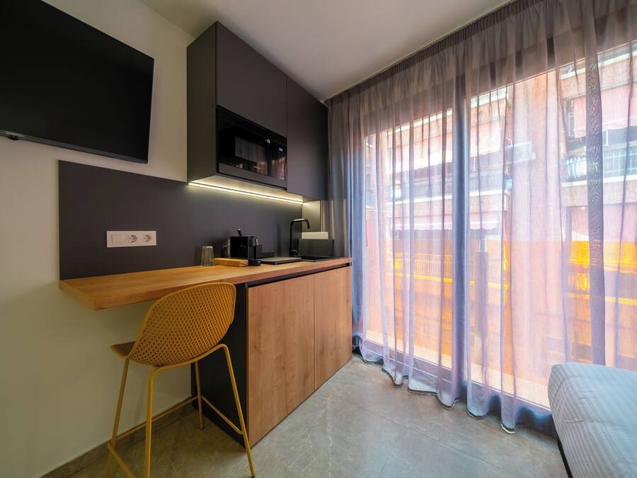 Una cocina moderna con encimera de madera, microondas integrado y una silla.