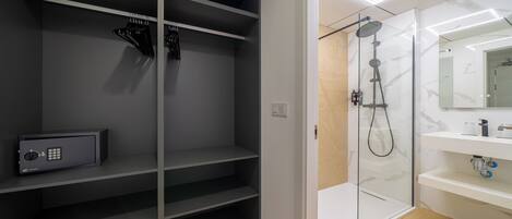 A modern bathroom with a walk-in shower, a built-in safe, and a vanity with a mirror.