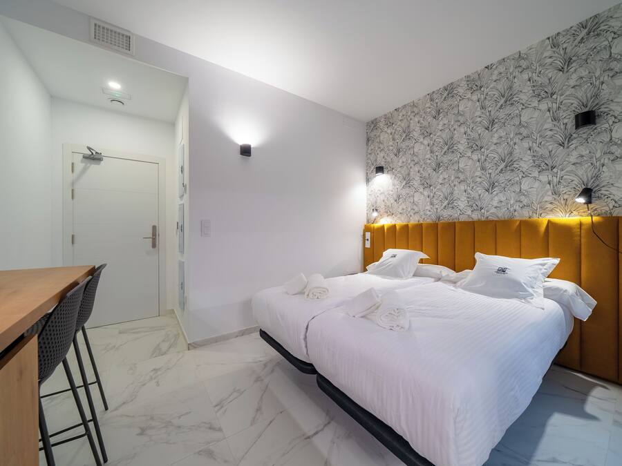 A hotel room with a bed, a wooden desk, and a chair.