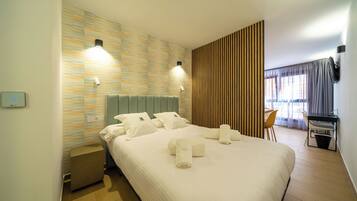 Quarto de hotel com uma cama grande, duas luminárias de cabeceira, uma escrivaninha e uma cadeira.