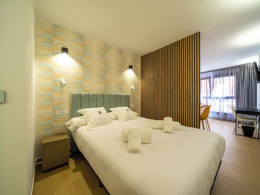 Quarto de hotel com uma cama grande, duas luminárias de cabeceira, uma escrivaninha e uma cadeira.