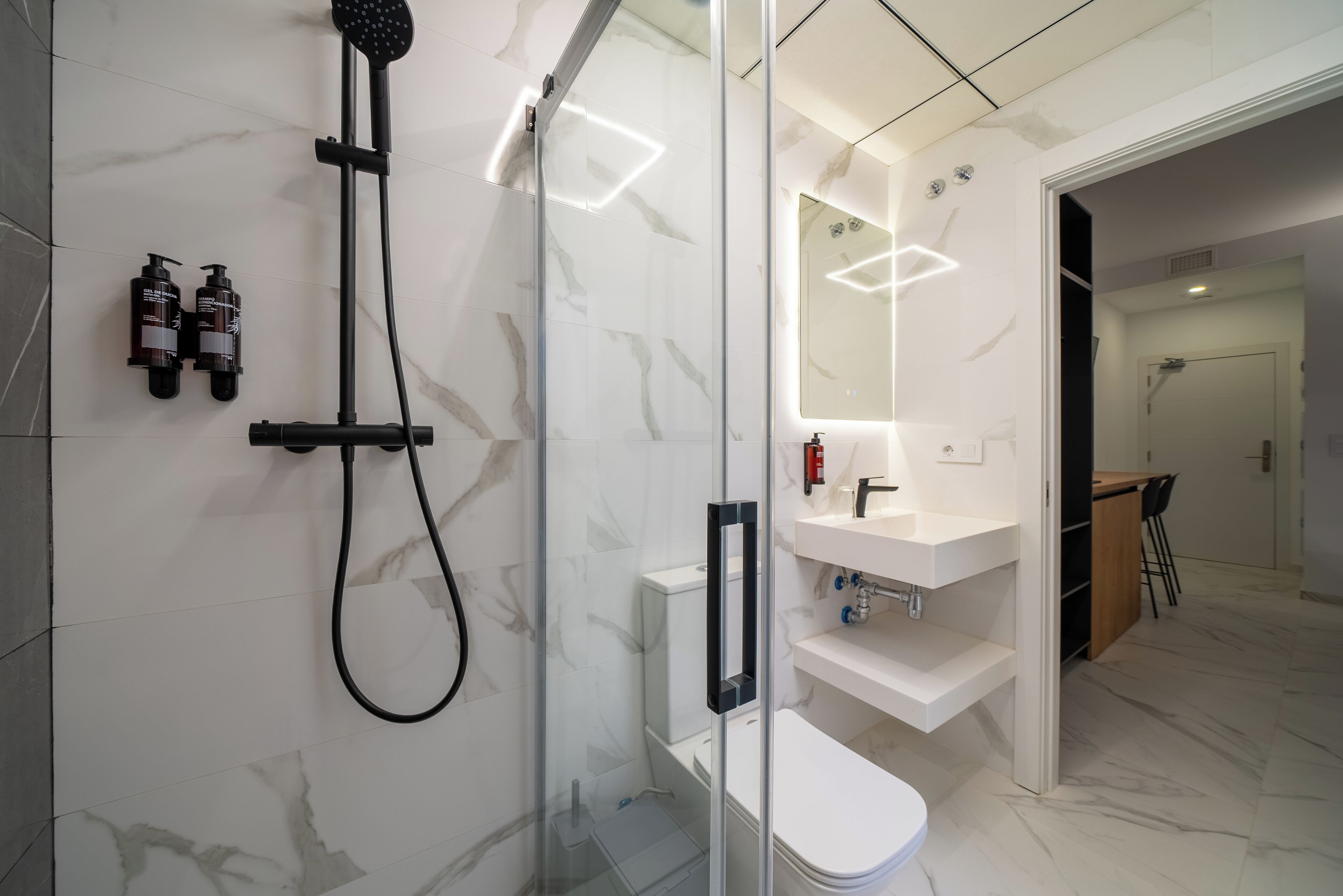 A modern bathroom with a glass-enclosed shower, a white toilet, and a vanity with a mirror.