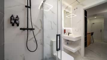 A modern bathroom with a glass-enclosed shower, a white toilet, and a vanity with a mirror.