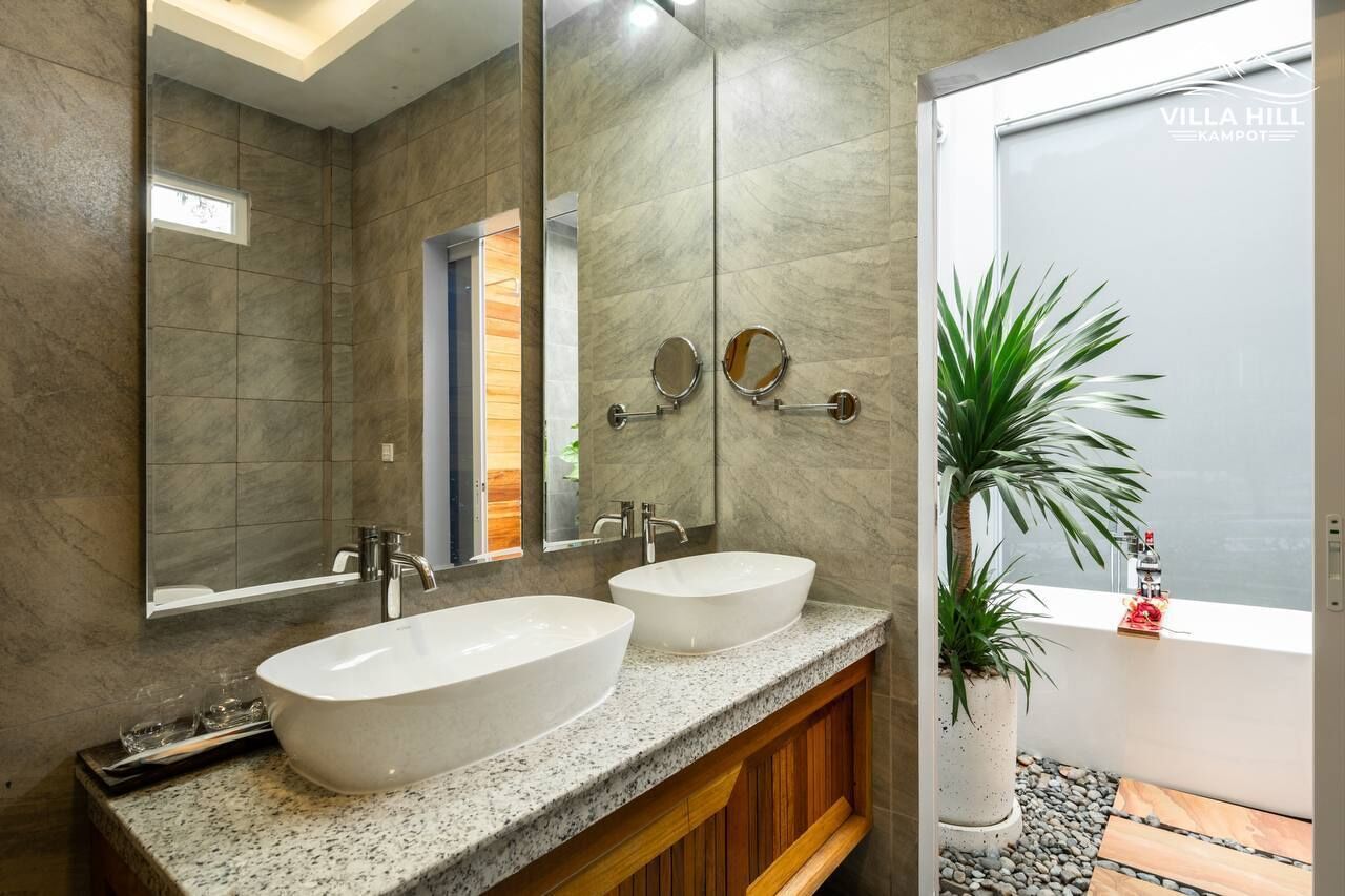 Un baño con dos lavamanos, un espejo grande y una planta en maceta.
