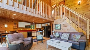A spacious living area with a wooden interior, a sofa set, a dining table, and a kitchen in the background. - Unusual Latitude Limit 7 3 Bedroom Villa (Raymond)