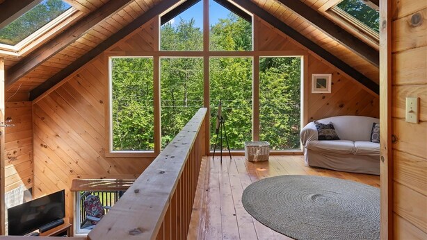 A wooden interior with a high ceiling, large windows, a sofa, and a television. - Unusual Latitude Limit 7 3 Bedroom Villa (Raymond)