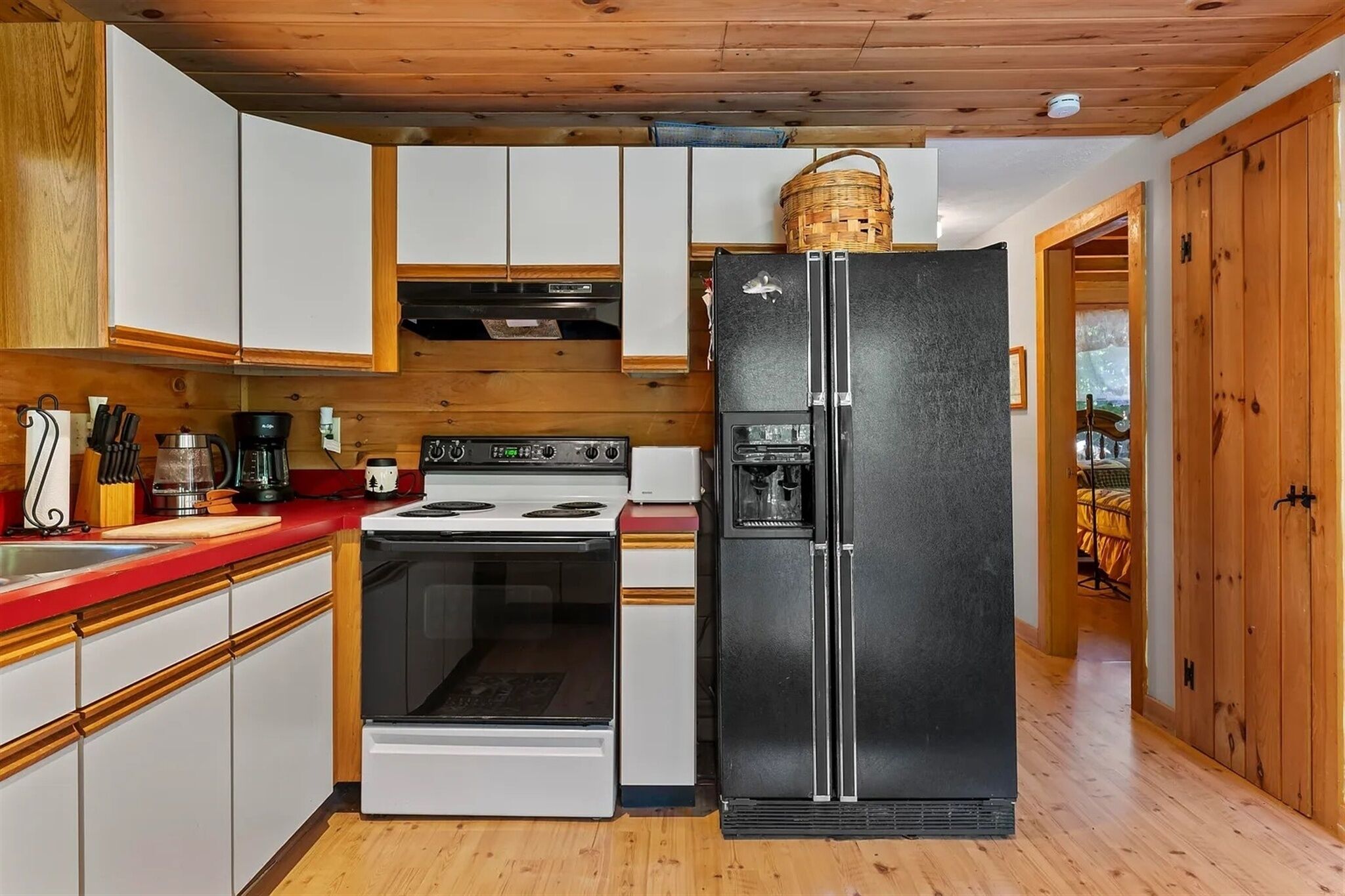 A compact kitchen with white cabinets, a black refrigerator, a stove, and a sink.