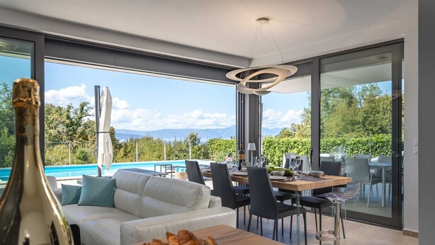 A modern dining area with a pool view, a white sofa, and a table with food and drinks. - Villa Luxor With Heated Pool (Malinska-Dubasnica)