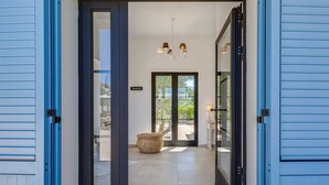 A hallway with a large glass door leading to a balcony, a woven basket, and a chandelier. - Villa Afrodita With Private Pool (Krk)