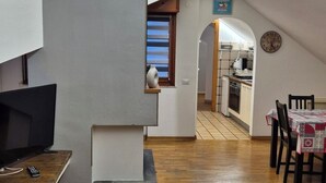 Moderni keittiö, jossa on ruokailutila, televisio ja seinällä oleva kello.