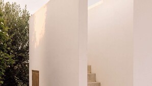 A staircase leading to an upper level, surrounded by white walls and a small door. - Casas de Arroz - Cabin (Possanco - Comporta)