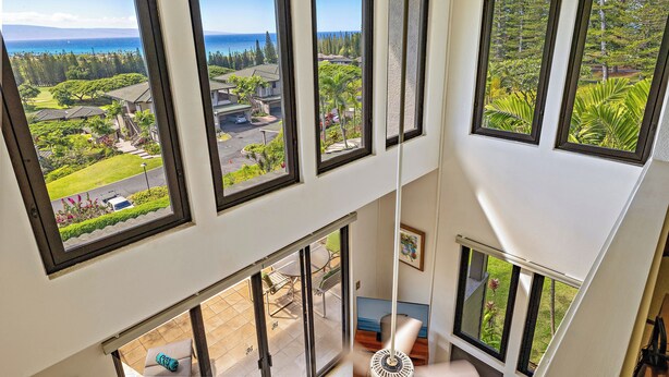 A high-rise interior with multiple large windows offering expansive views of a lush landscape and the ocean.