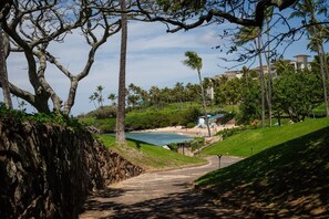 Un sendero que lleva a una playa con palmeras y un edificio al fondo.