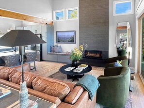 Una sala de estar moderna con chimenea, sofás de cuero y un comedor.